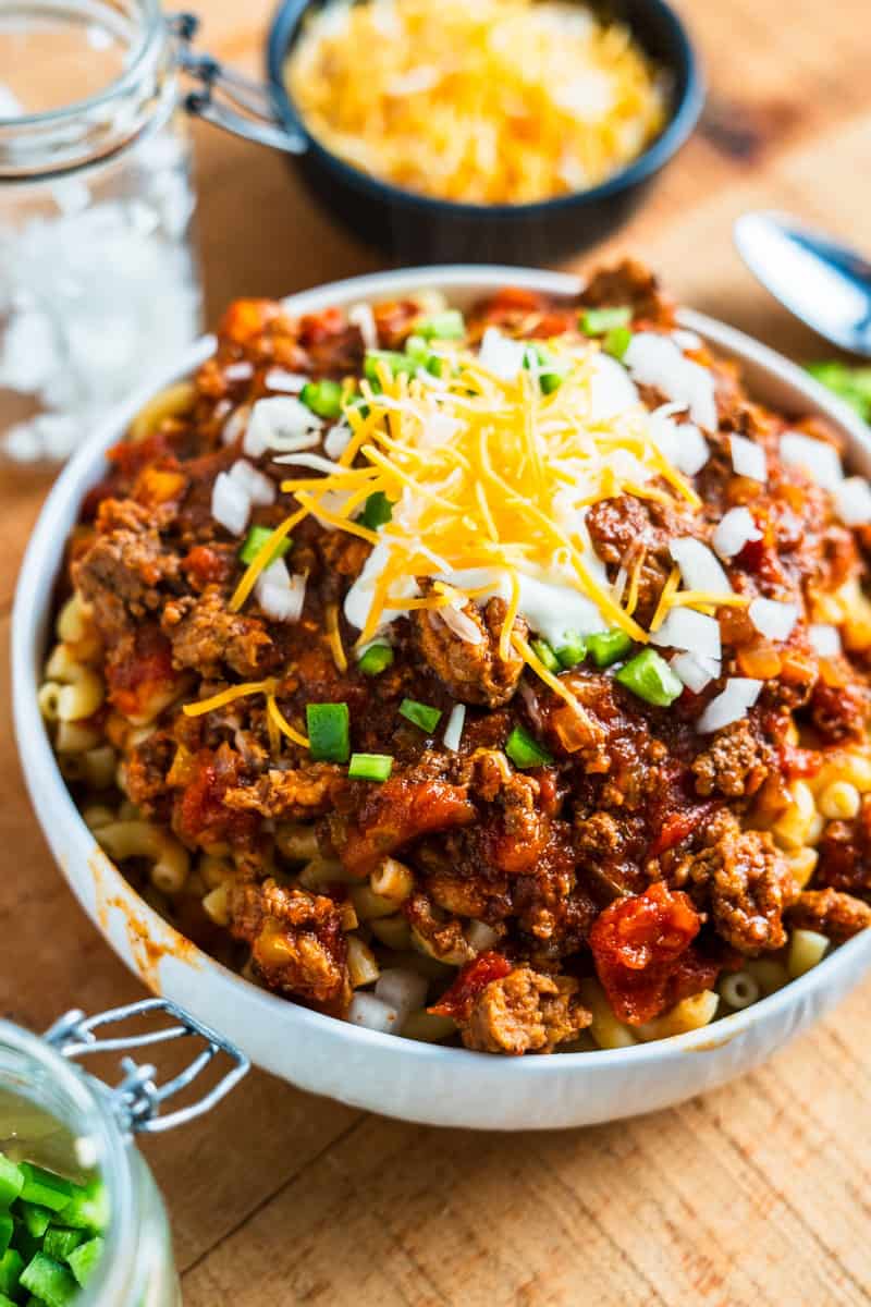 Bowl of Chili Mac topped with sour cream, onion, and jalapenos