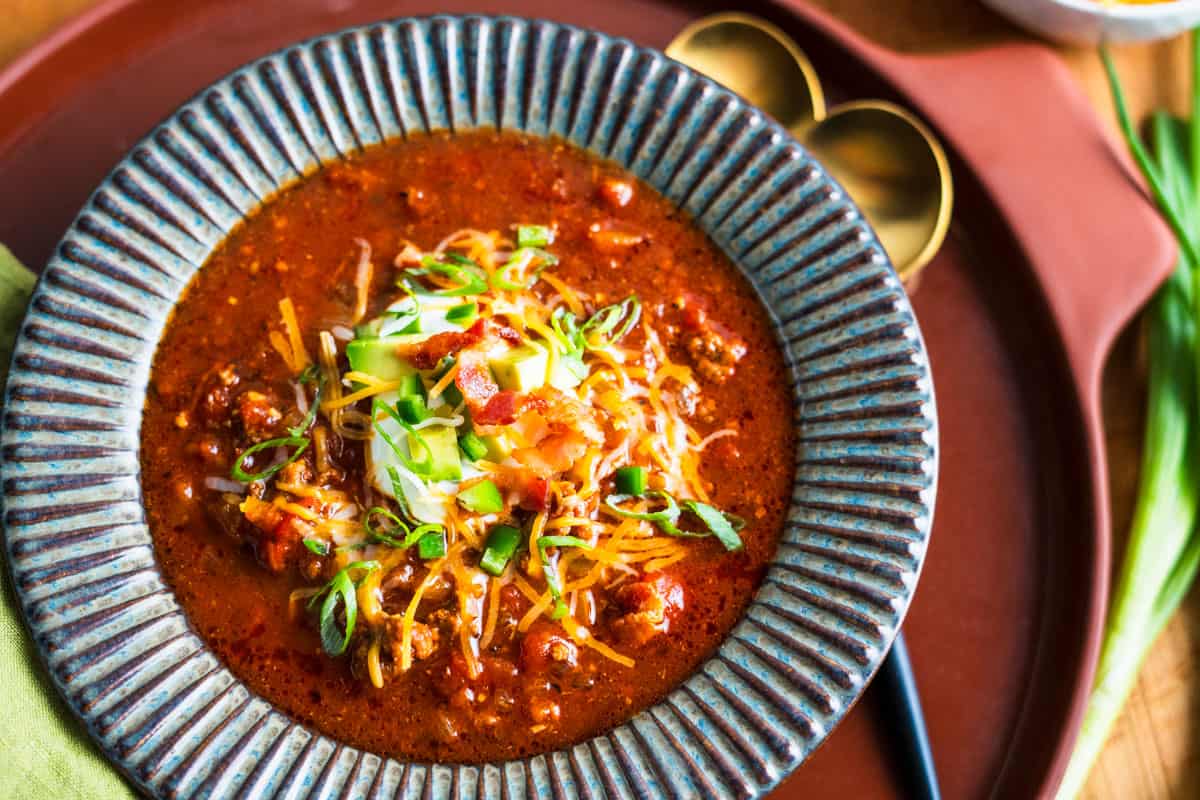 bowl of chili with cheddar cheese and bacon on top