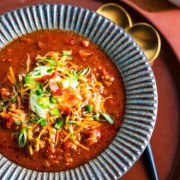 Bowl of Chili with cheddar cheese, avocado, and green onion