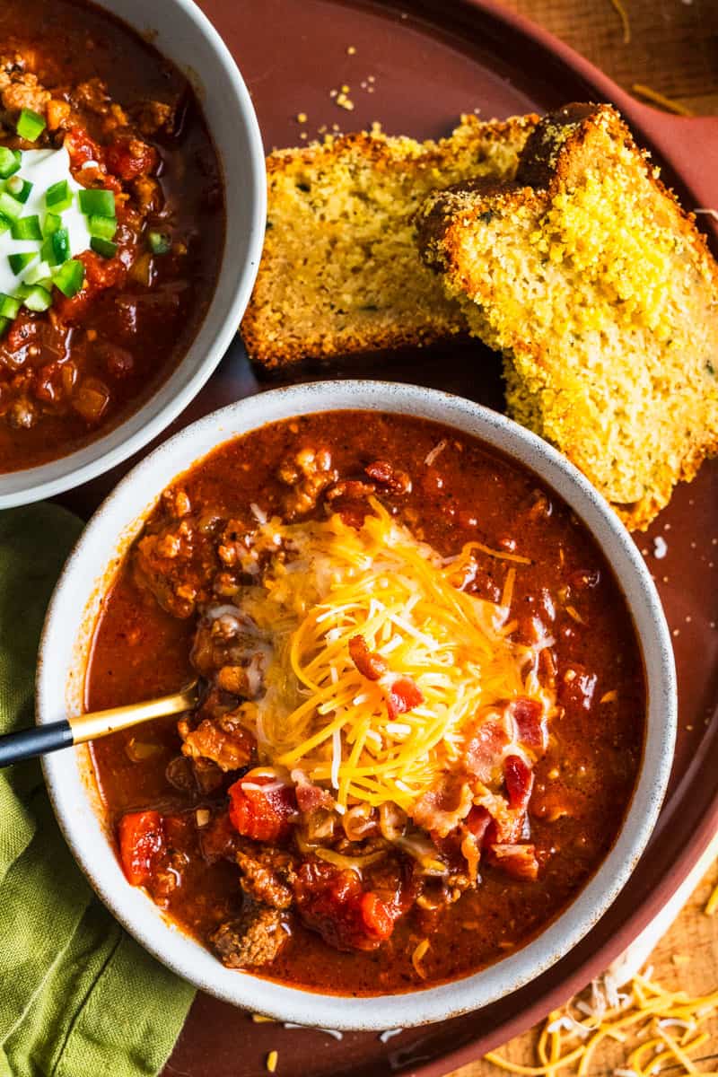 bowl of chili with cheddar cheese and bacon on top