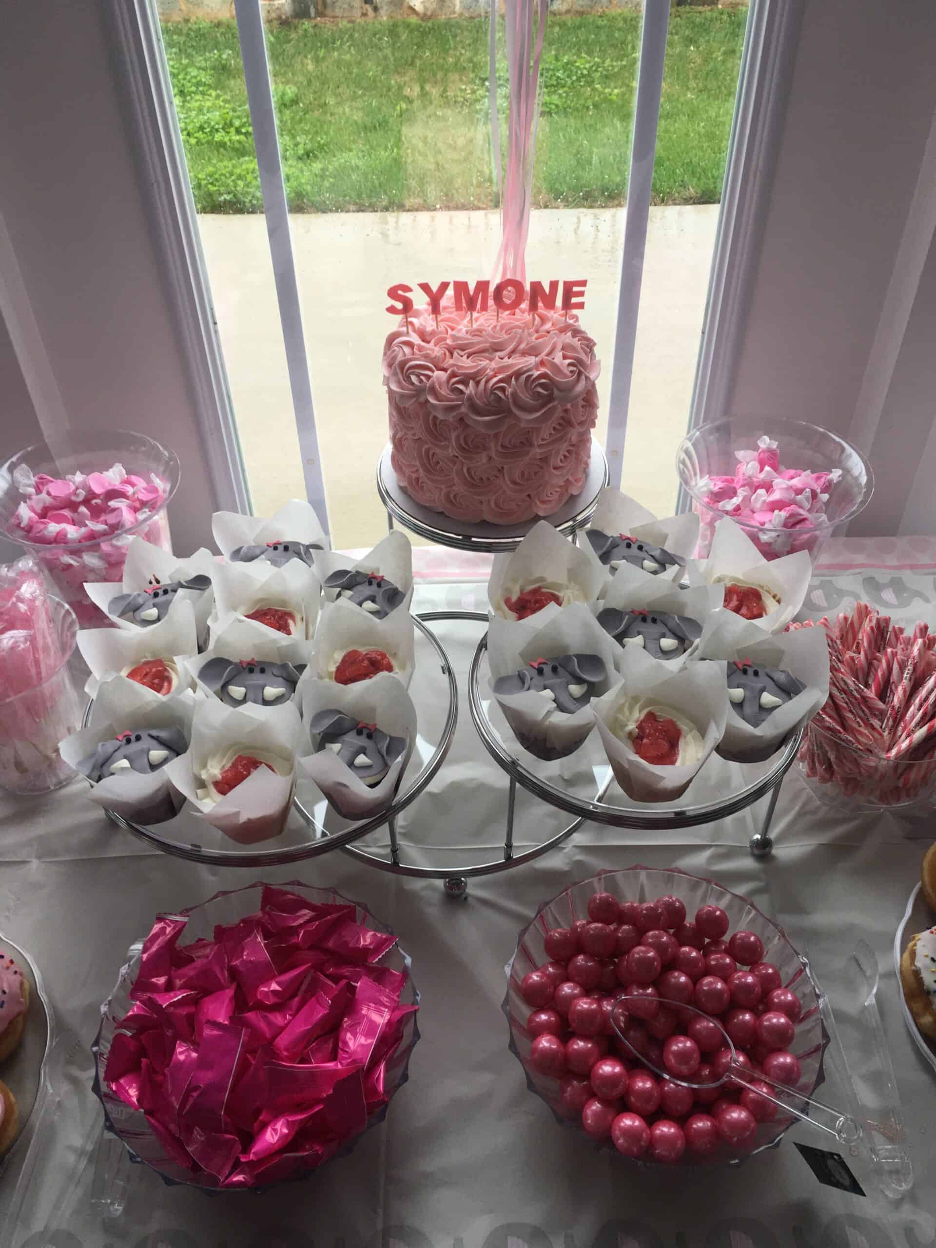 a baby shower dessert table, with strawberry shortcake cupcakes, a rosette covered cake and fondant elephants cupcakes 