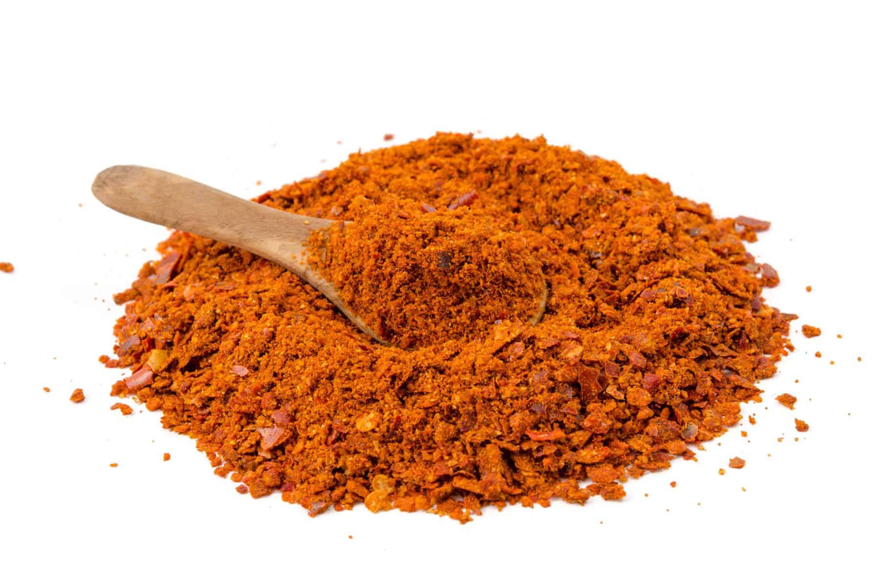 harissa powder on a white background with a wooden spoon in the middle
