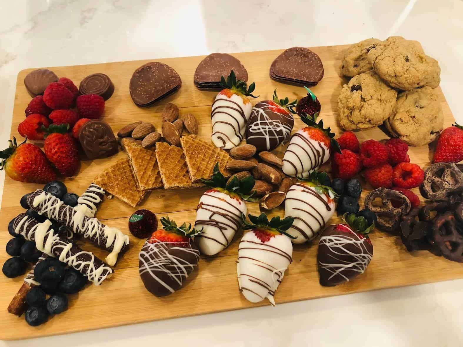 a dessert board made with chocolate covered strawberries, pretzels, fresh fruits, nuts and cookies