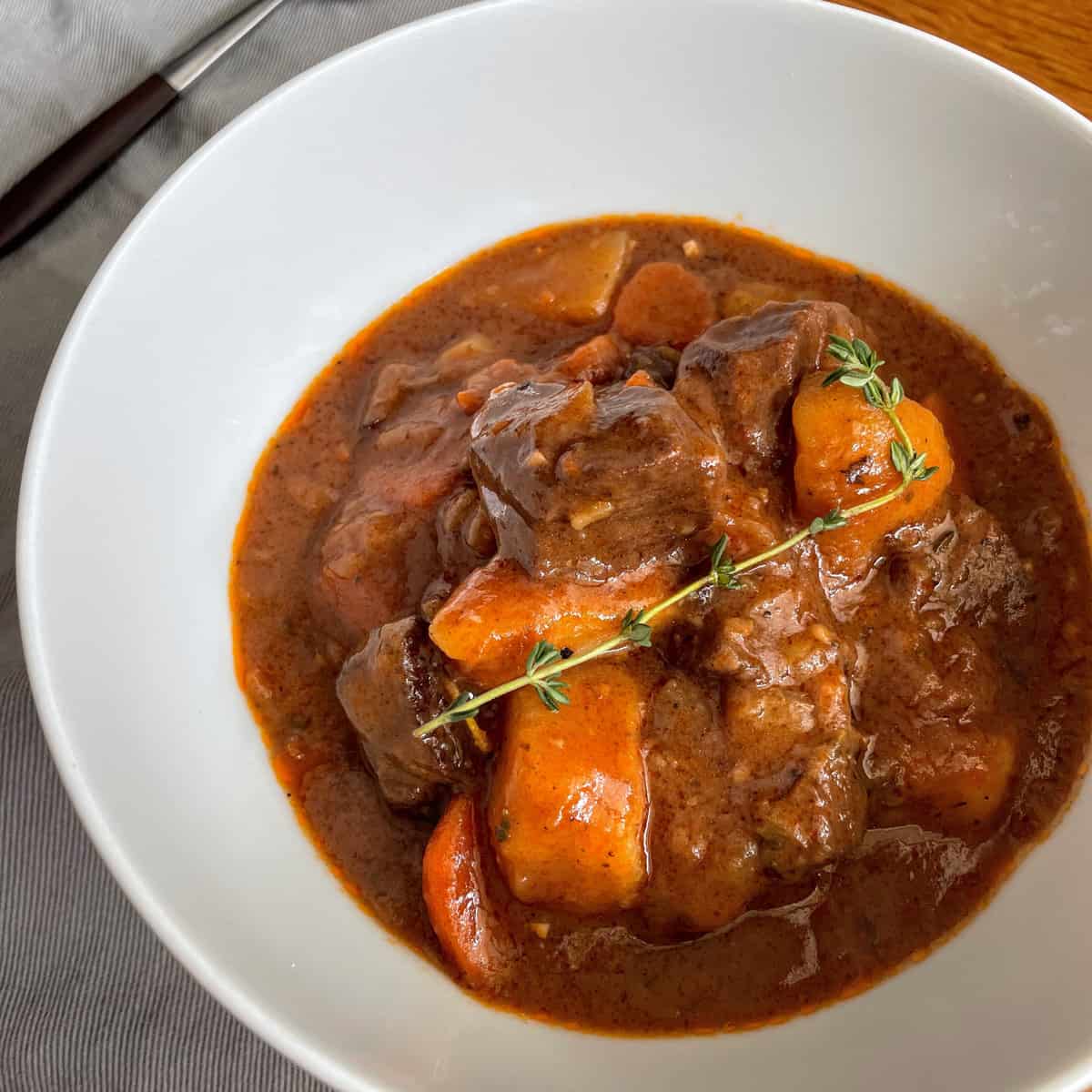 Beef Stew in a bowl with chunky carrots and fresh thyme