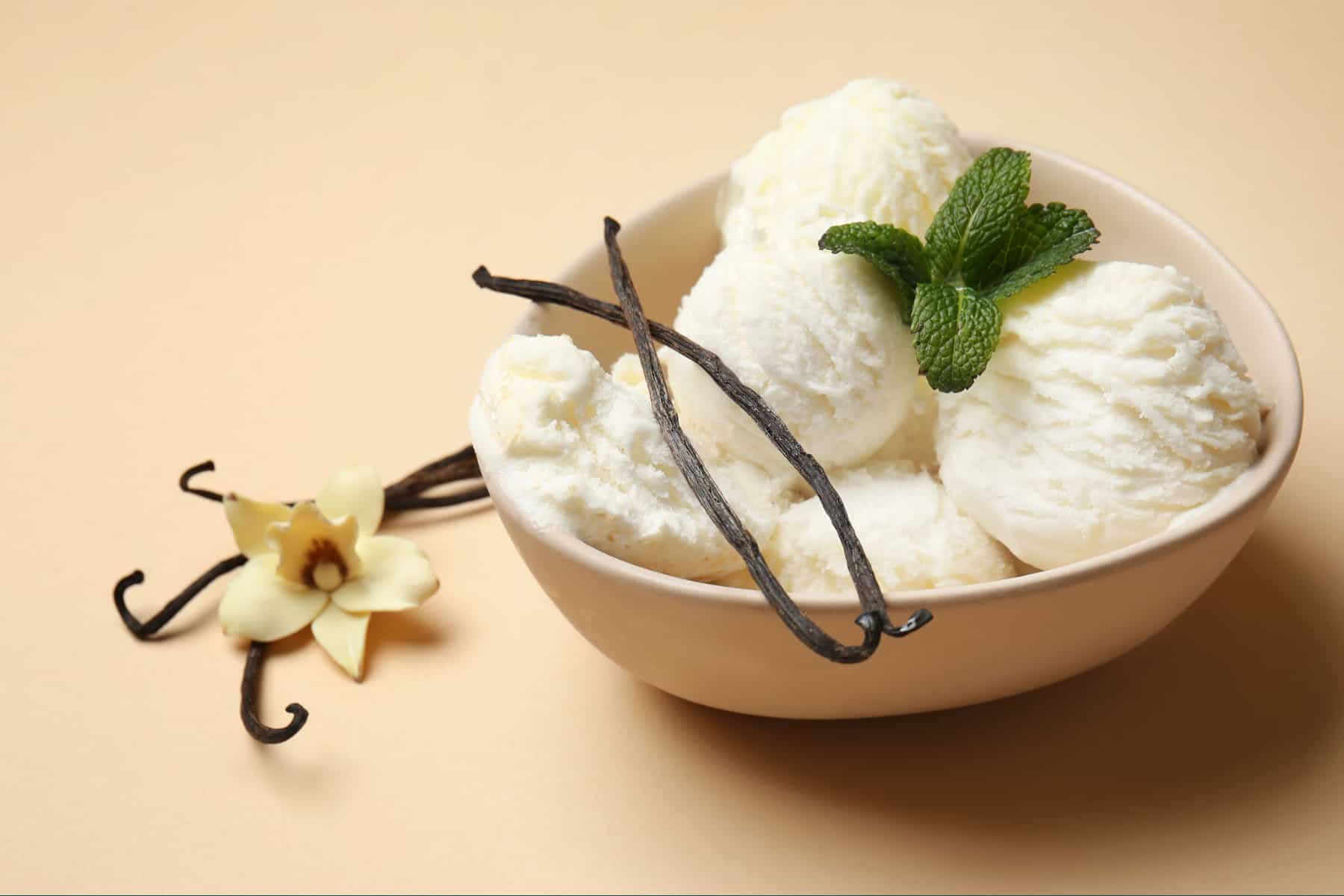Vanilla ice cream in a bowl with fresh mint and vanilla beans 