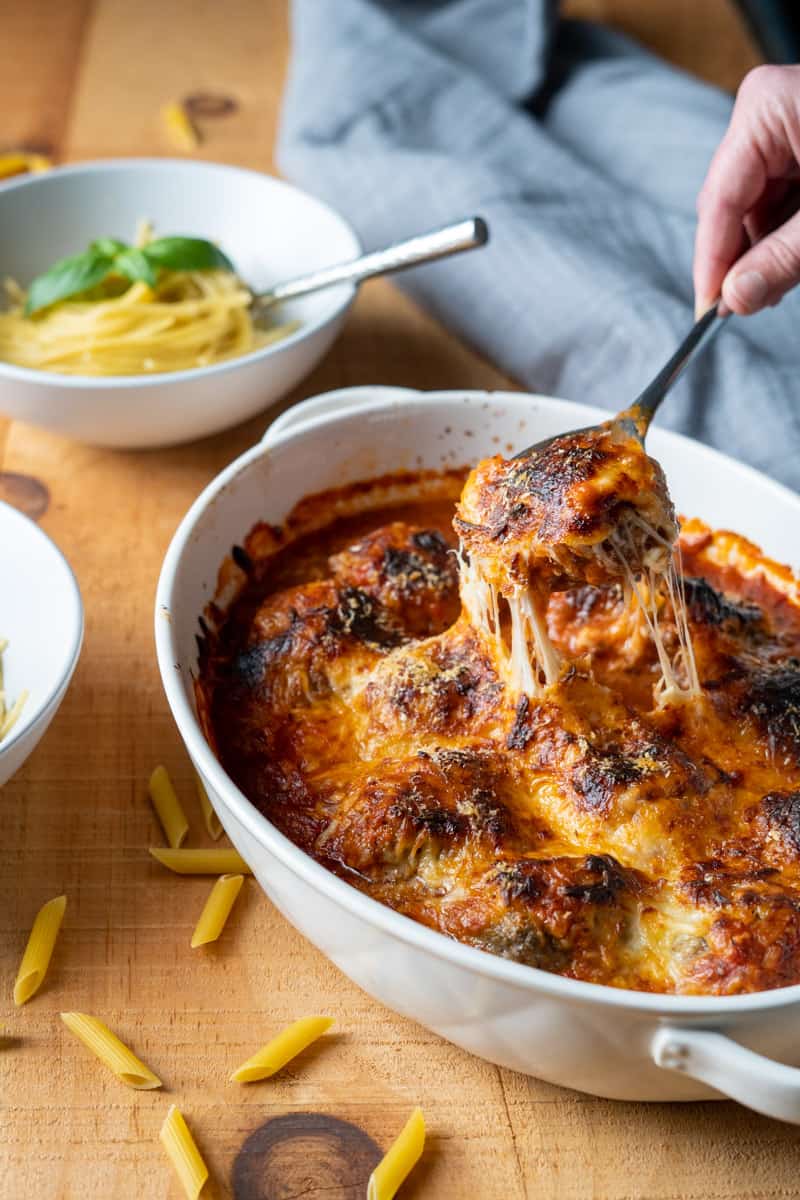 Baked Italian Meatballs being served over spaghetti