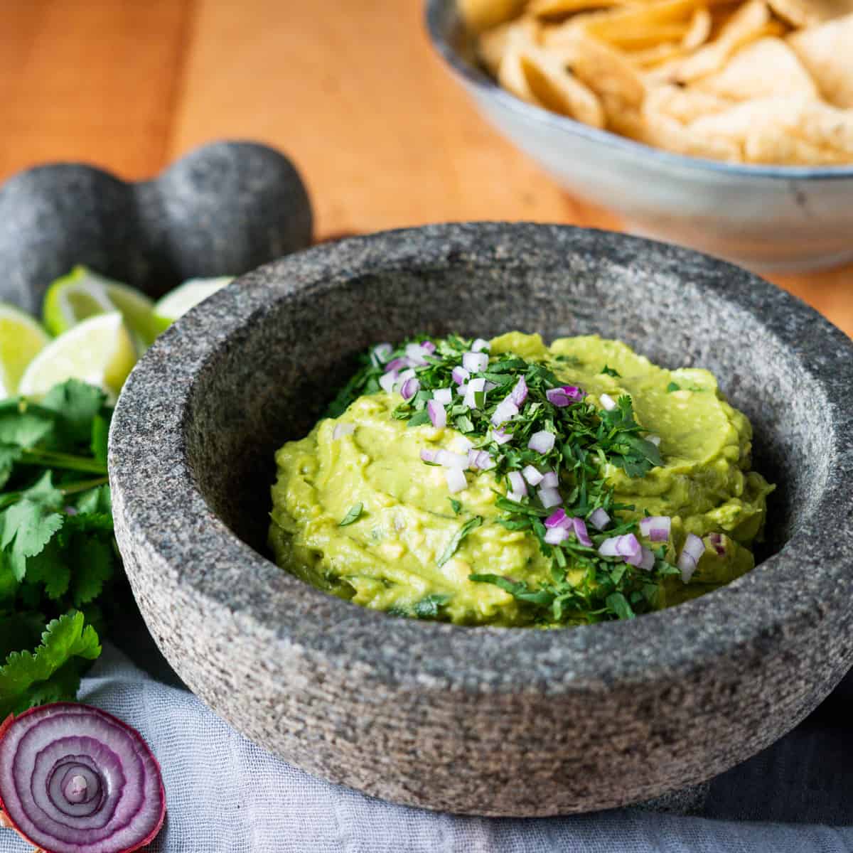 Homemade guacamole in a mortal and pestal garnished with cilantro and red onion