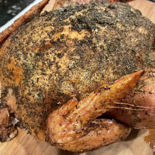 a whole Smoked Chicken with Italian seasoning on a cutting board