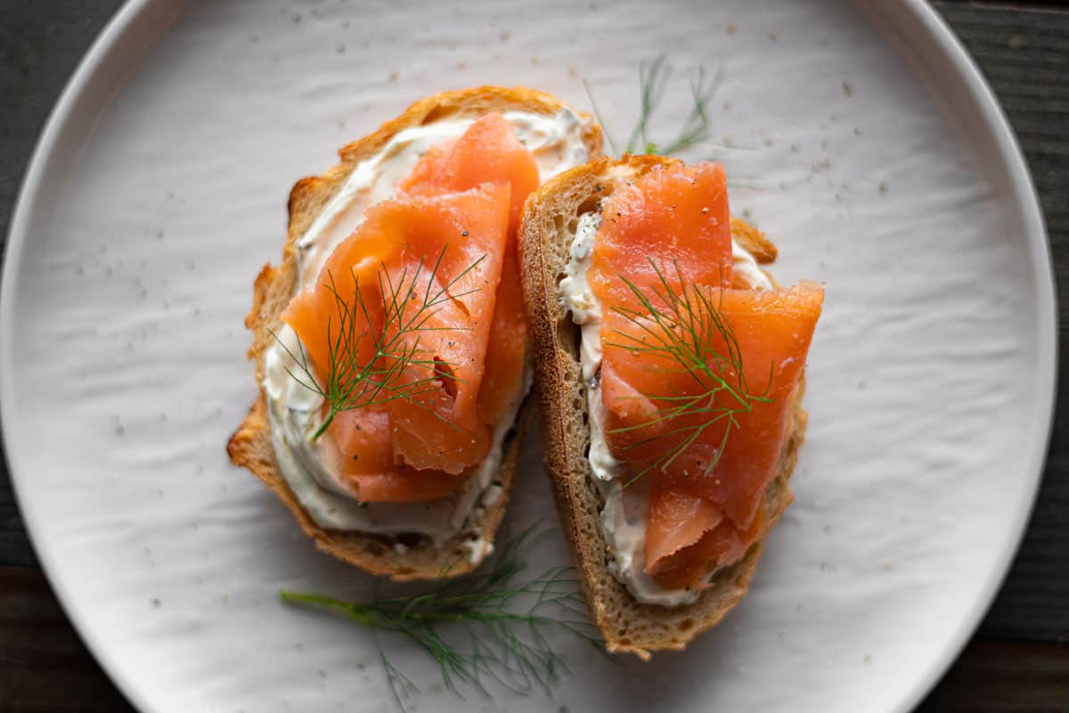 smoked salmon toast, garnished with fresh dill on a white plate. 