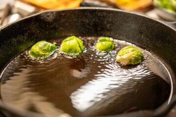 halved brussel sprouts searing in a cast iron pan