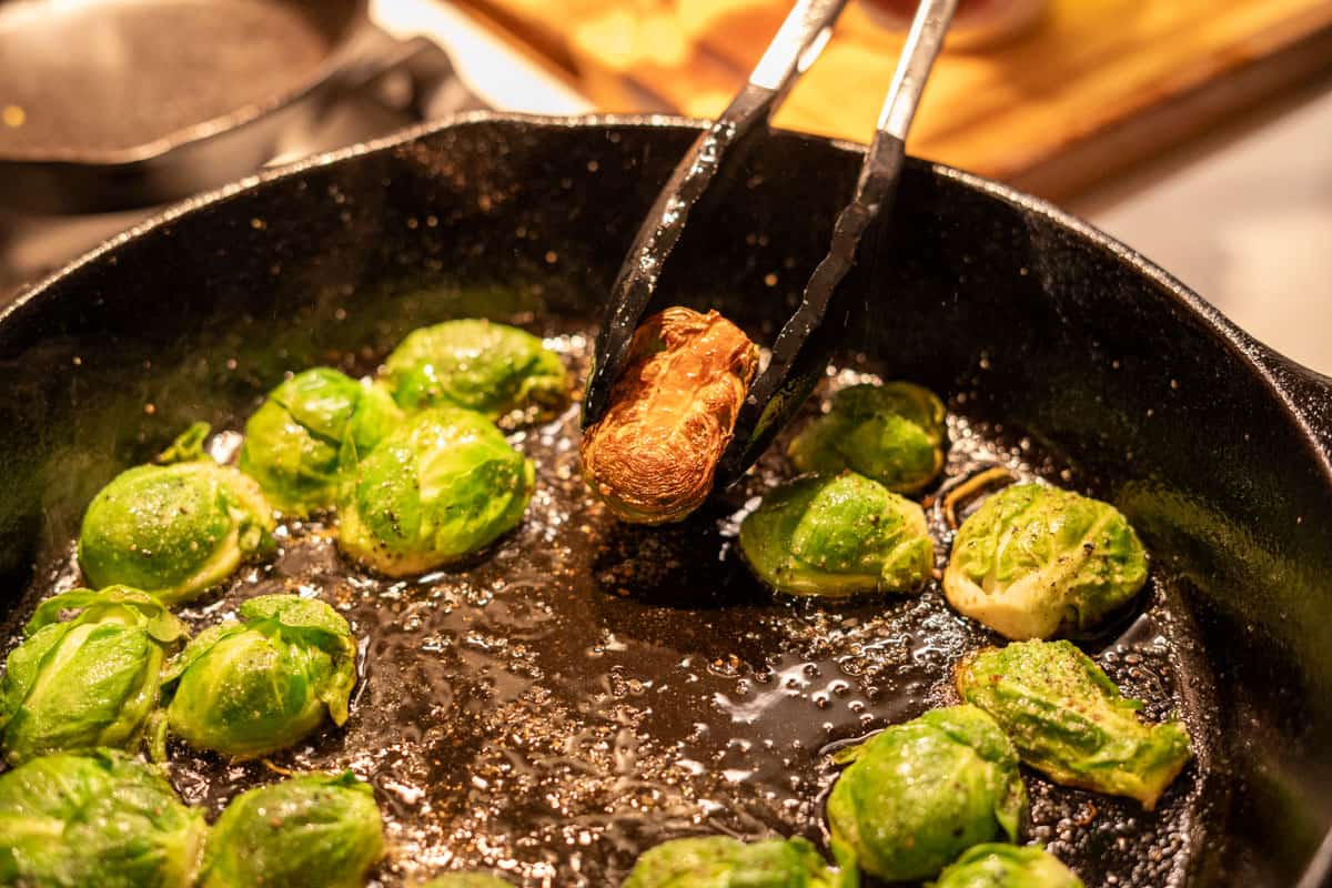 turning browned brussels sprouts in a cast iron pan.