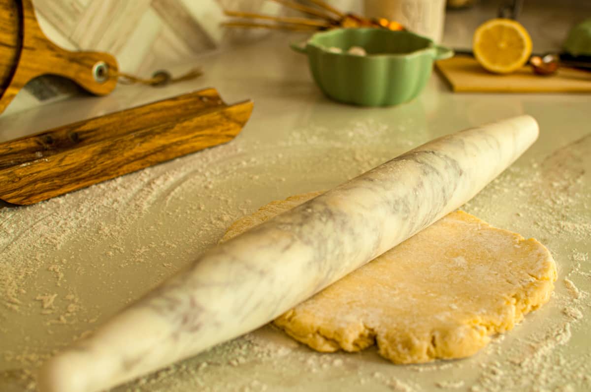 pie crust being rolled out with a marble rolling pin