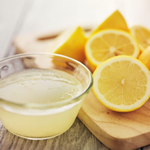 Bowl of fresh-squeezed lemon juice with halved lemons