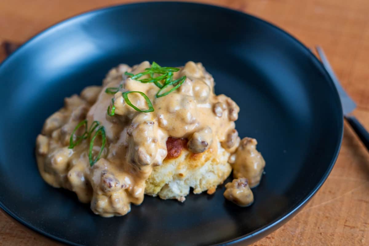 Chorizo sausage gravy over a biscuit on a black plate 