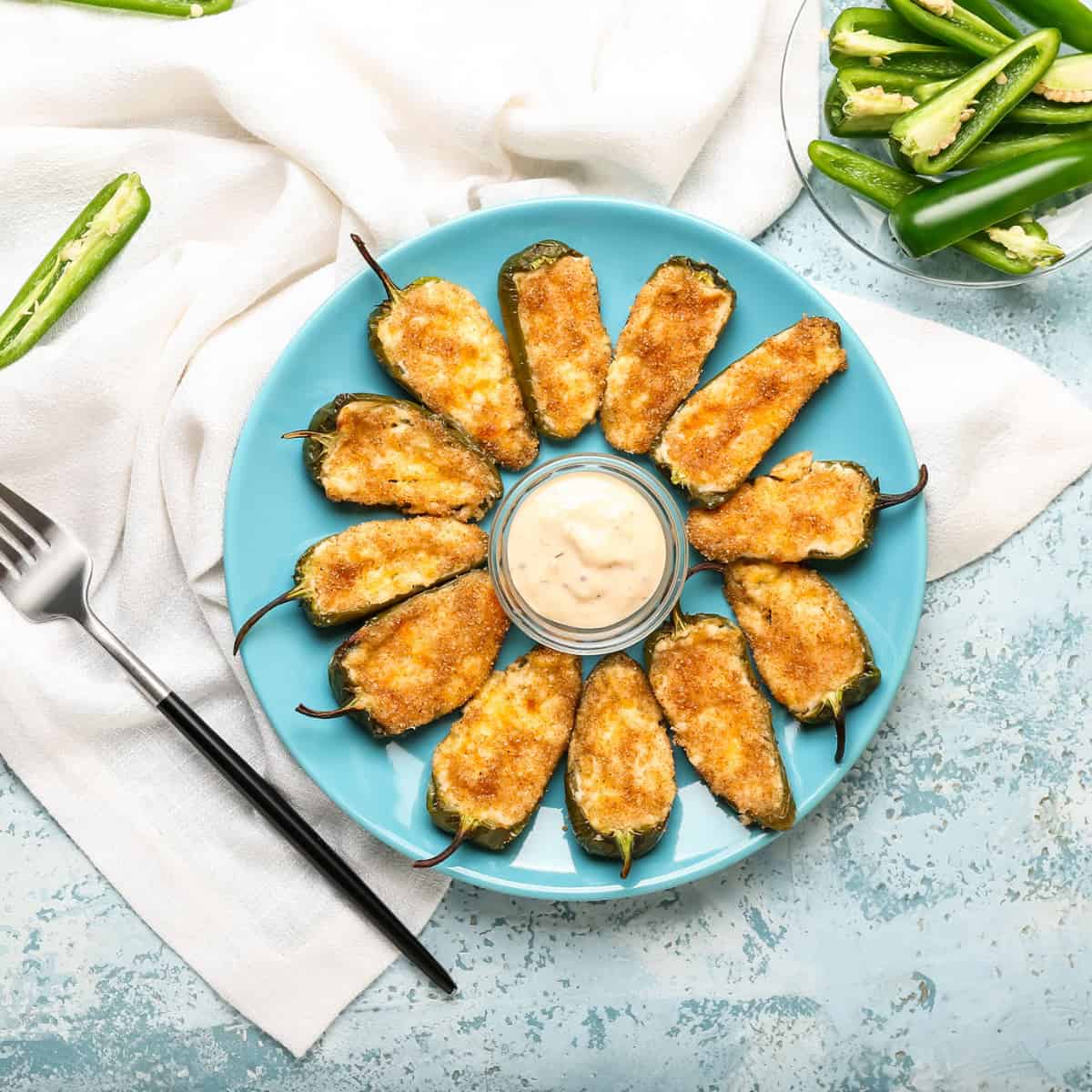 Ring of breadcrumb topped jalapeno poppers on a blue plate 