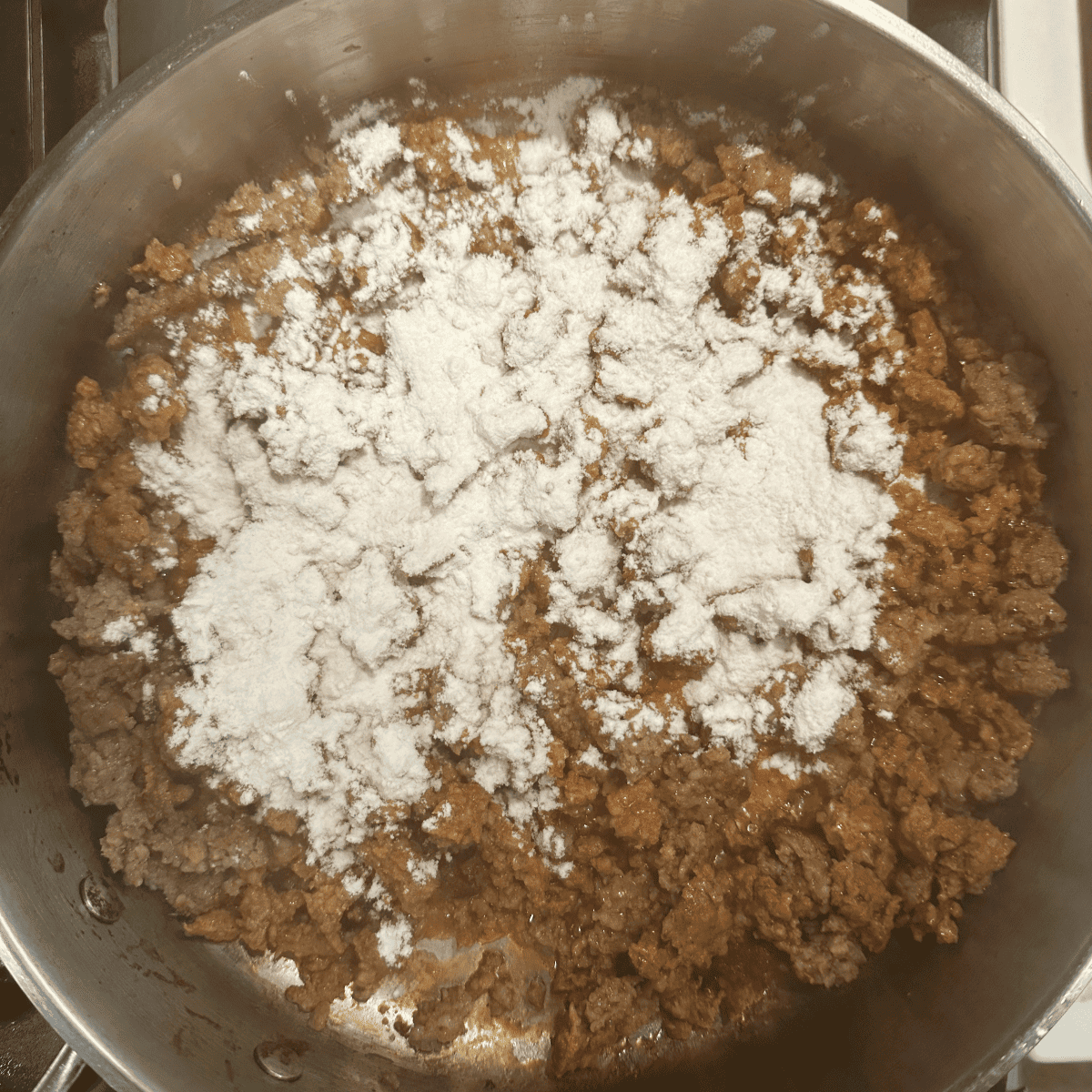 Flour being added on top of browned chorizo