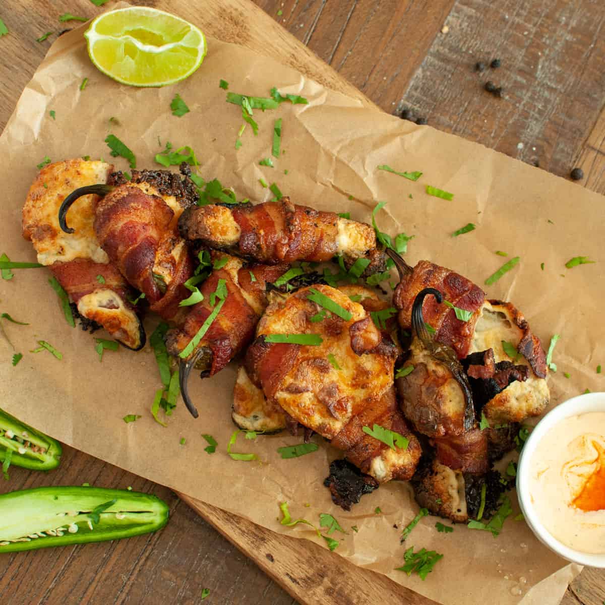 Smoked Jalapeno Poppers on parchment paper with lime and dip