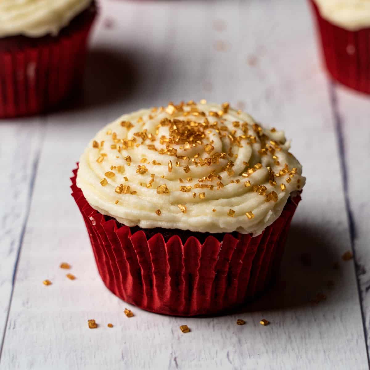 a red velvet cupcake with gold crystal like sprinkles 
