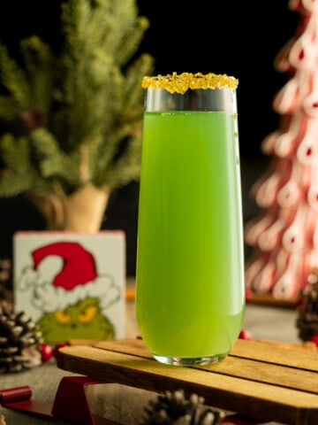 Grinch themed mimosa with a gold sprinkle rim