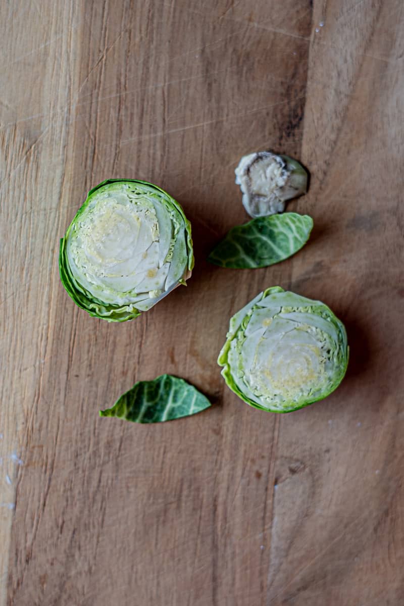 Brussels Sprout cut in half on a wood cutting board