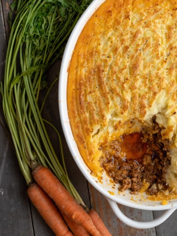 Shepherd's Pie with a spoonful missing next to fresh carrots