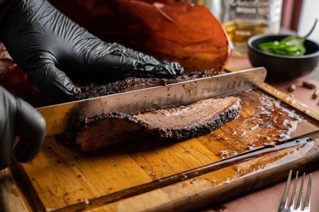 Pellet smoker brisket being sliced on a wooden cutting board