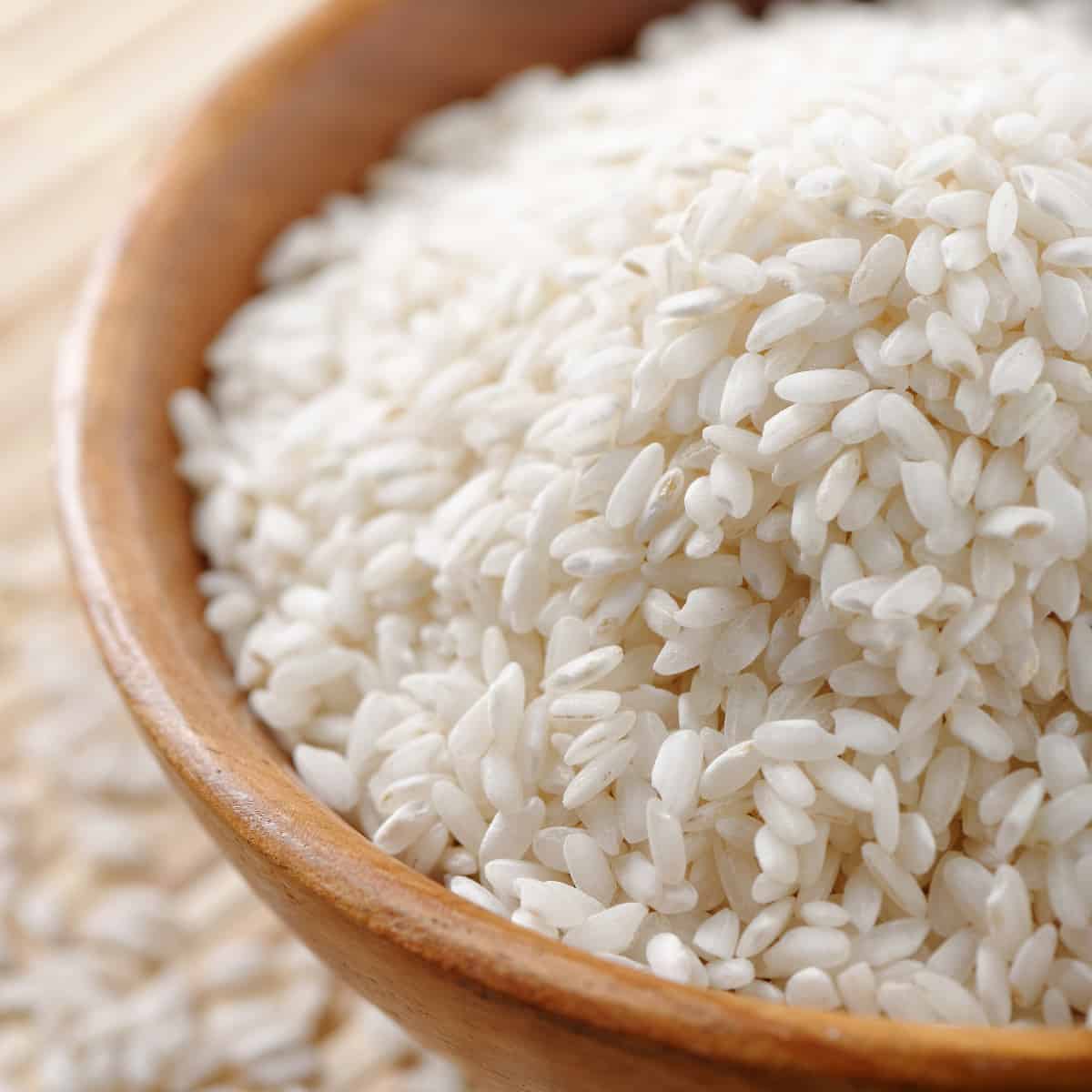 up close view of arborio rice in a wooden bowl. 