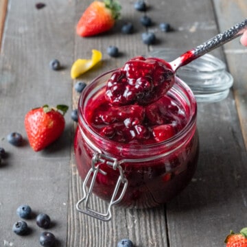 A spoonful of Berry Compote from a glass jar