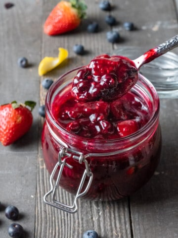 A spoonful of Berry Compote from a glass jar