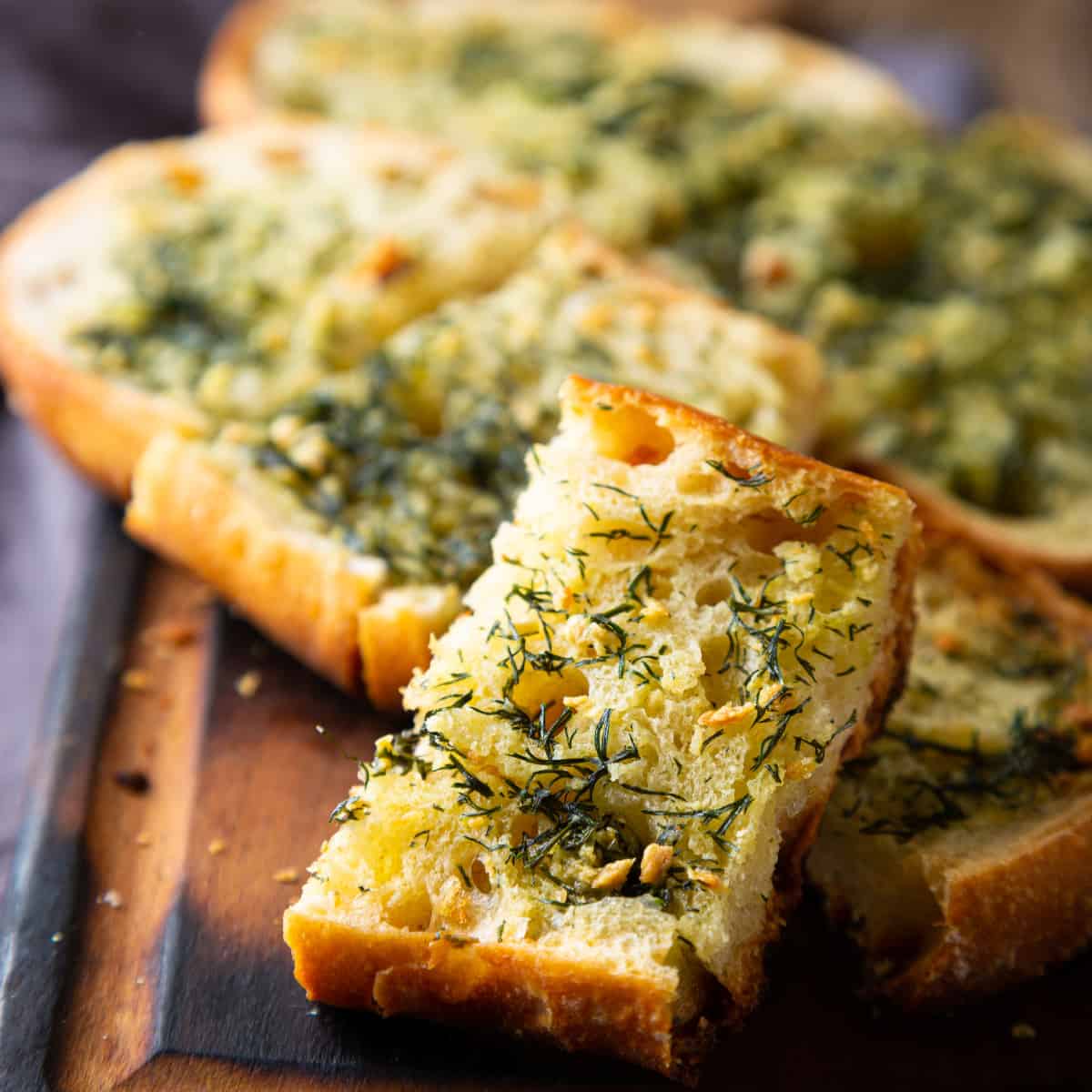 french garlic bread with herbs and parmesan cheese on a wood board