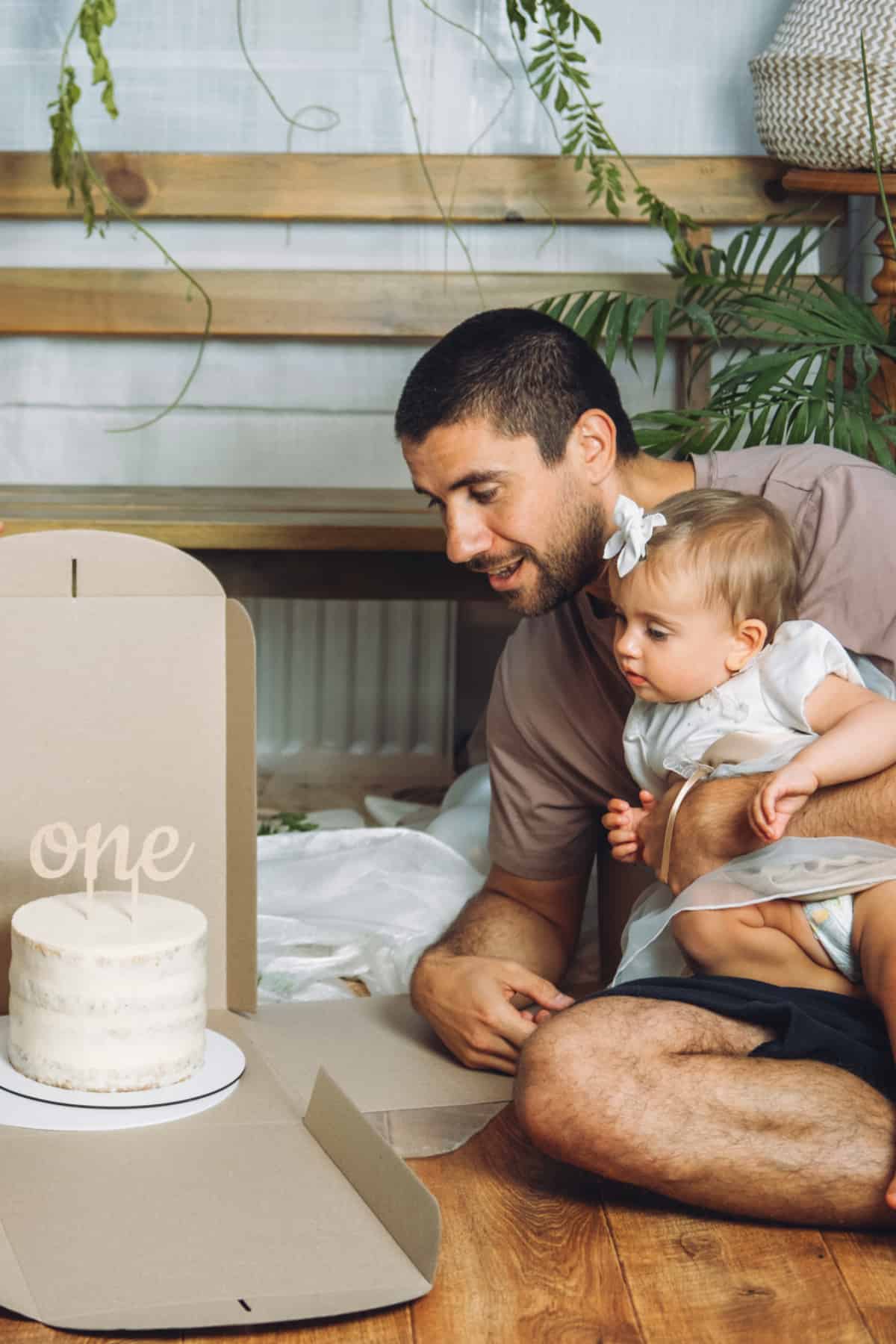 Dad and baby sitting on floor looking at a cake