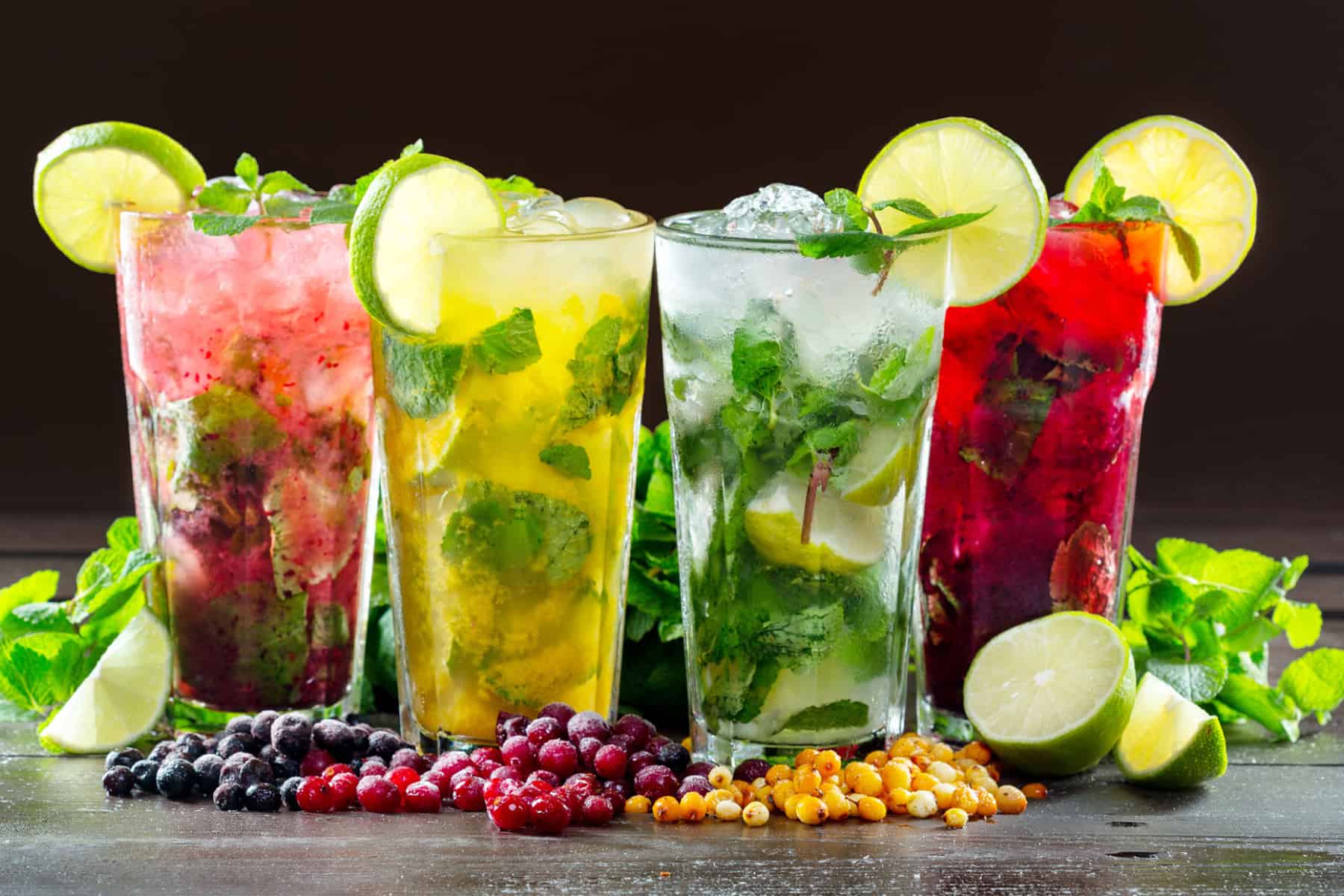 four cocktails of different colors all featuring mint