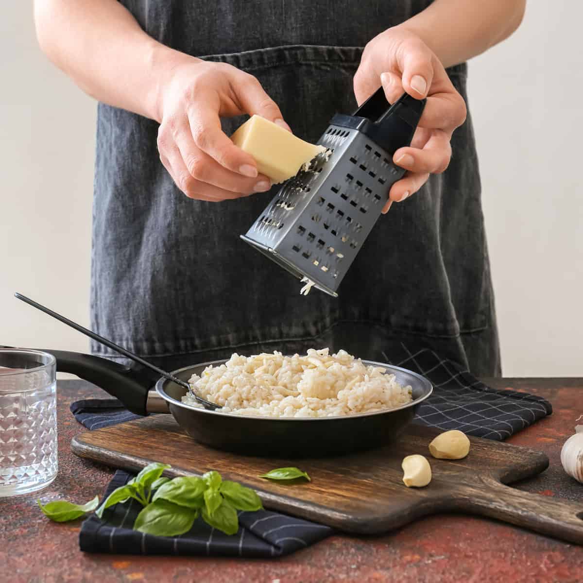 Risotto in a pan, grating parmesan over top