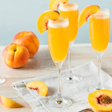 Peach Bellini cocktails with peach slices on glasses.
