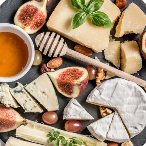 Cheese board with figs and a honey pot with wooden dipper
