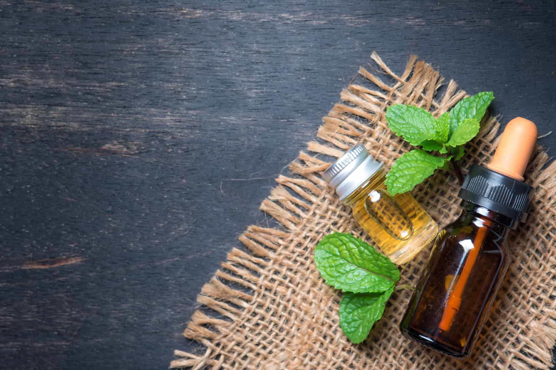 Small bottle of oil sitting next to fresh mint leaves