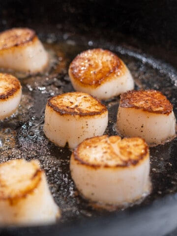 Scallops searing in a cast iron skillet