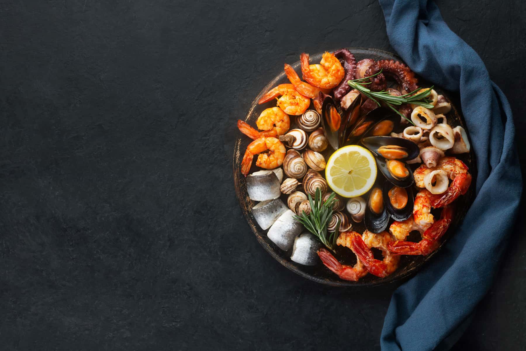 Shrimp, calamari, muscles, and octopus on a circular plate with a black background