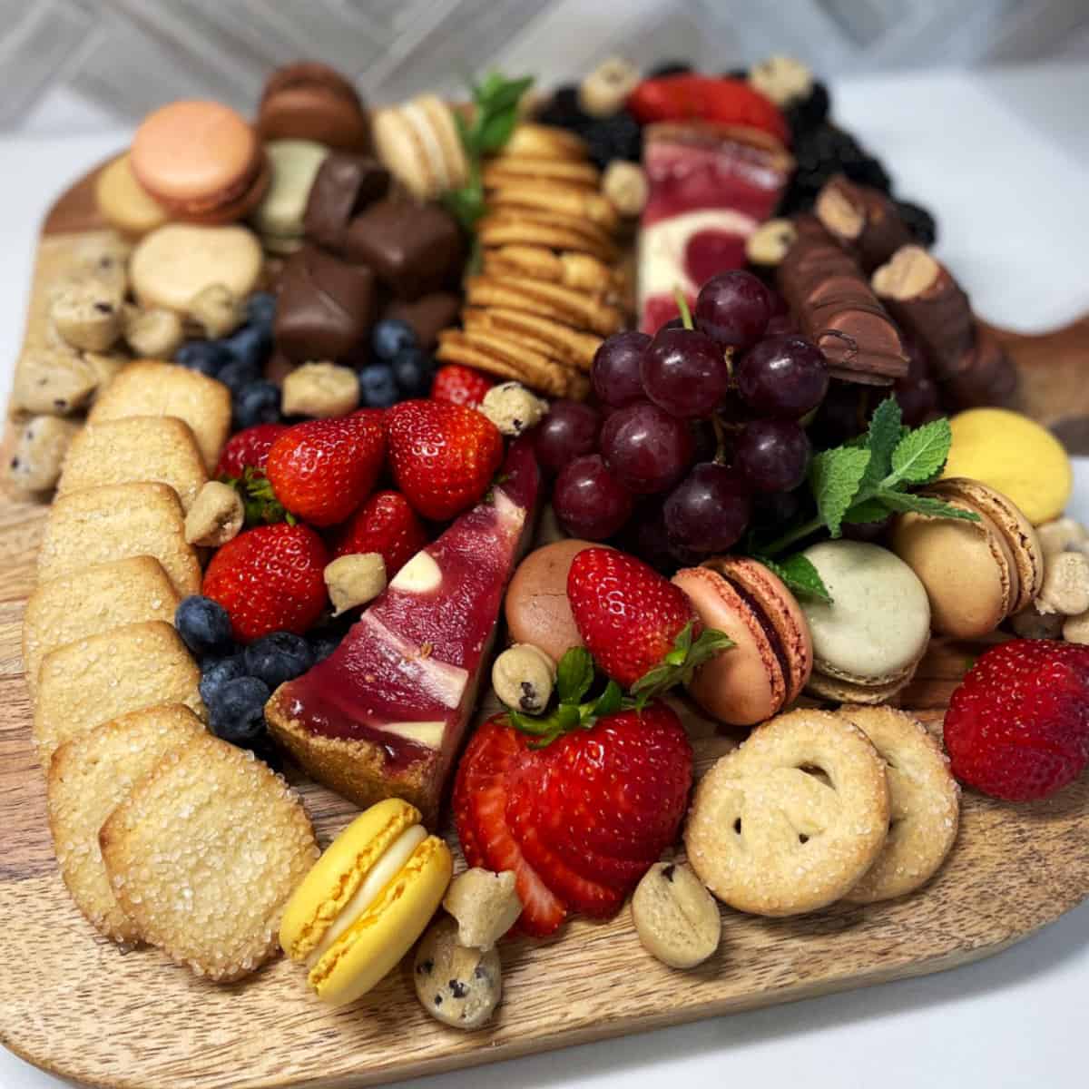 Dessert Charcuterie Board with cookies, chocolates, macaroons, cheesecake, and fresh fruit