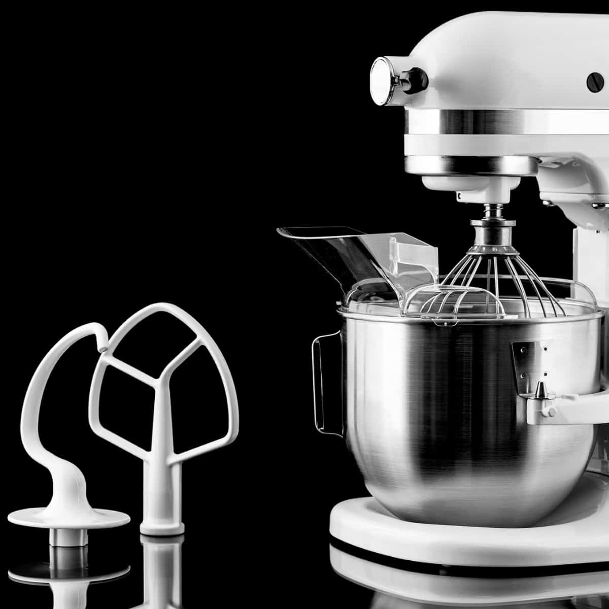 White kitchenaid with the standard attachments sitting nearby