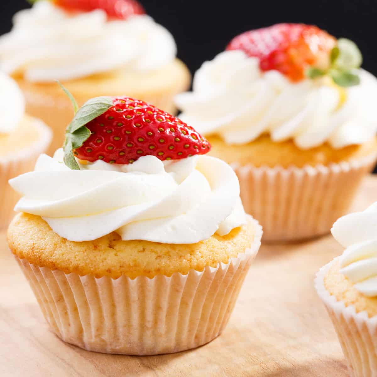 Whipped cream frosting on a vanilla cupcake with a sliced strawberry on top