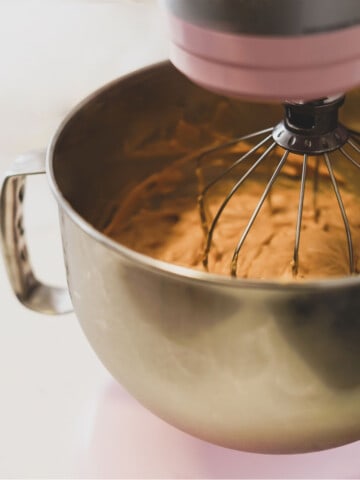 Close-up of KitchenAid mixer with whisk attachment mixing batter.