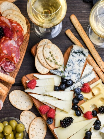 a table with a cheese board and a charcuterie board surrounded by wine and snacks