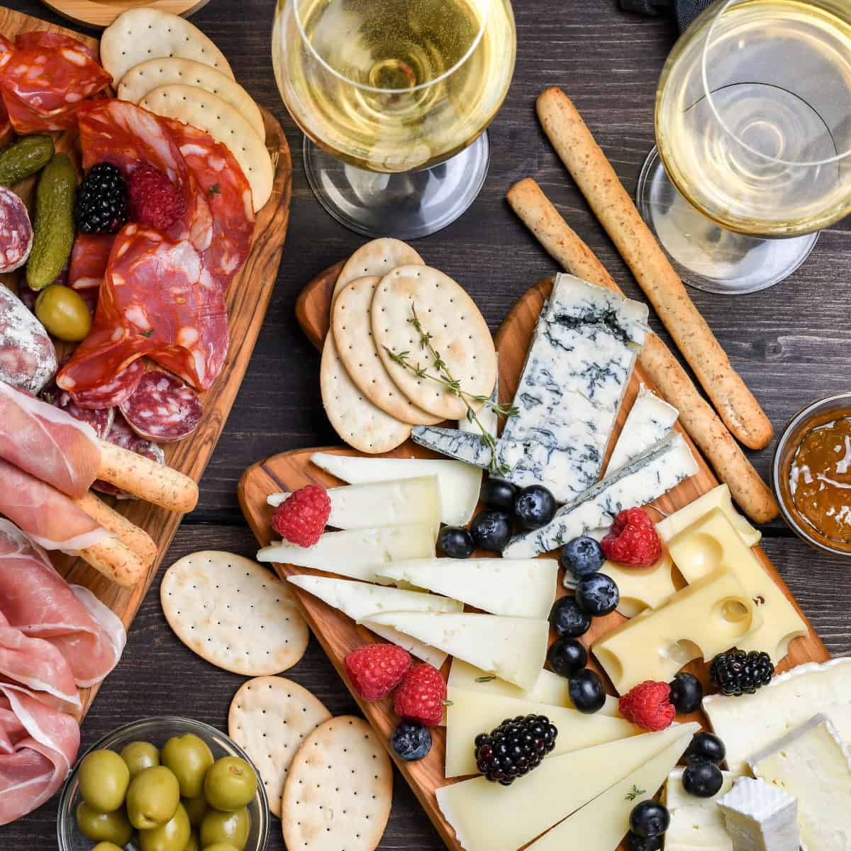 a table with a cheese board and a charcuterie board surrounded by wine and snacks