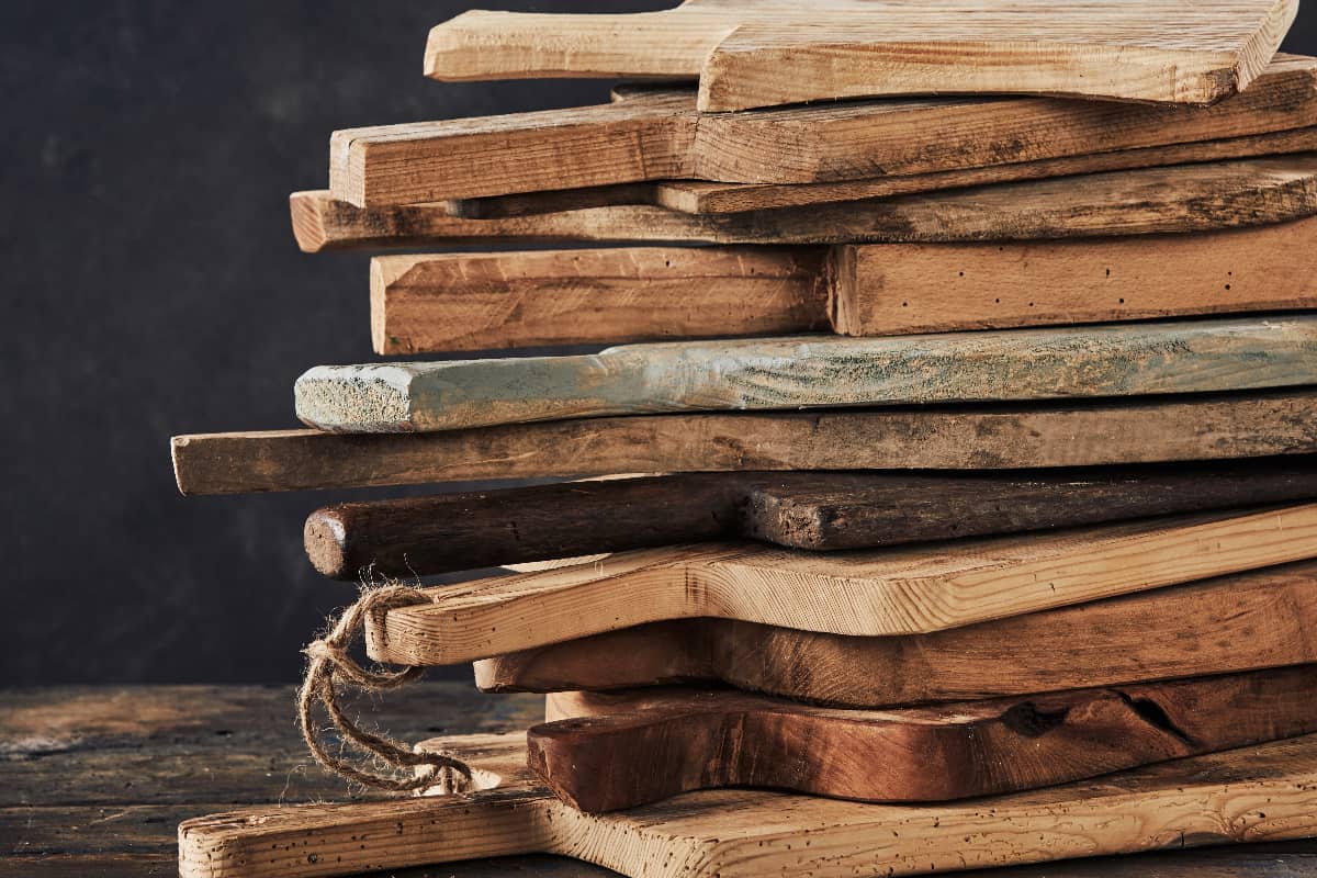 stack of a dozen antique charcuterie boards 