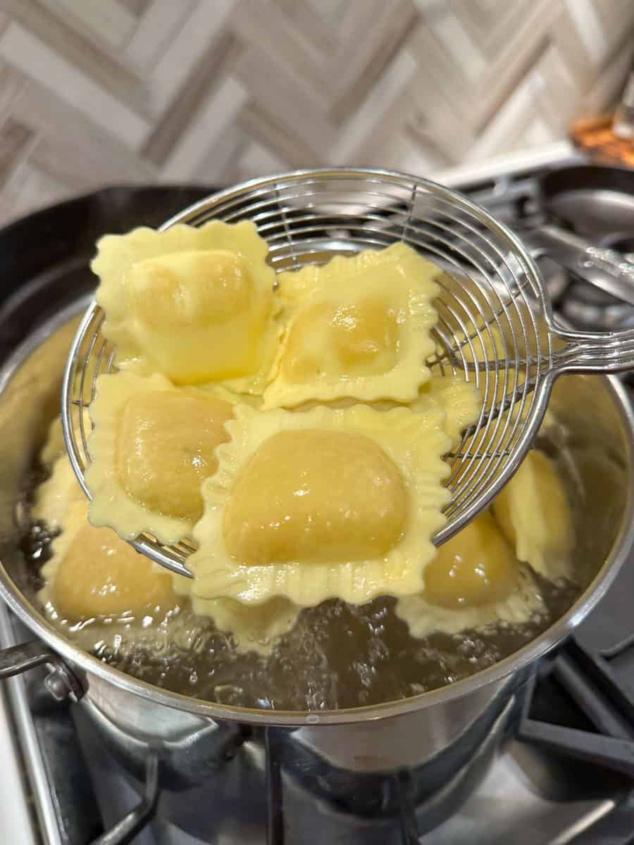 ravioli coming out of a pot of boiling water