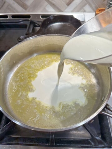 heavy cream being added to a pan that has been deglazed with white wine