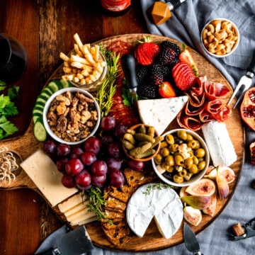 overhead view of a large charcuterie board with meats, cheese, fruit, and crackers.