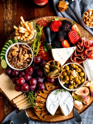 overhead view of a large charcuterie board with meats, cheese, fruit, and crackers.