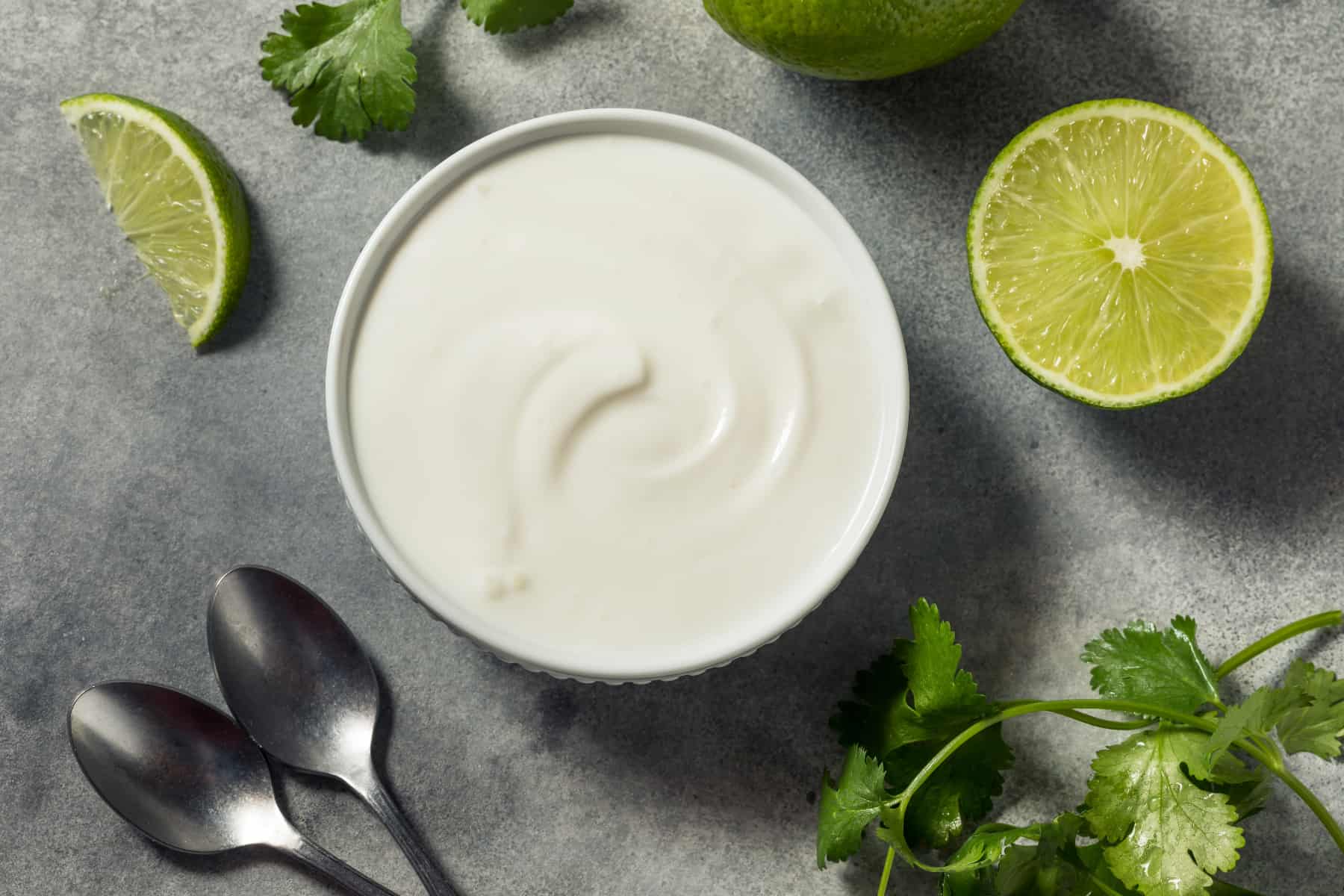 mexican crema in a bowl next tom limes and cilantro 